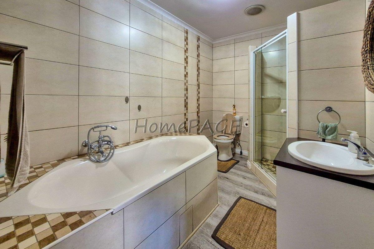 A functional bathroom featuring a built-in bathtub, separate shower enclosure, toilet, and a vanity basin with tiled wall finishes.