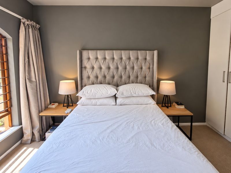 A well-maintained bedroom featuring a large arched window, neutral wall tones, and a spacious built-in wardrobe with clean finishes.