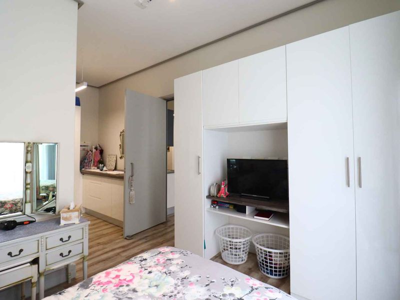 A well-maintained bedroom featuring modern laminate flooring and a large, white built-in wardrobe with integrated shelving.