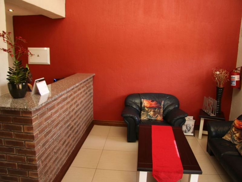 A reception area featuring a brick-faced counter with a granite top, ceramic tiled flooring, and a prominent red accent wall.