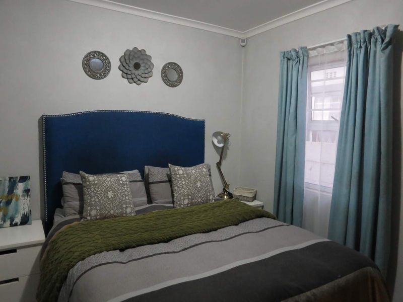 A cozy bedroom featuring neutral wall tones, coving, and a window with curtains, providing a comfortable and functional sleeping space.