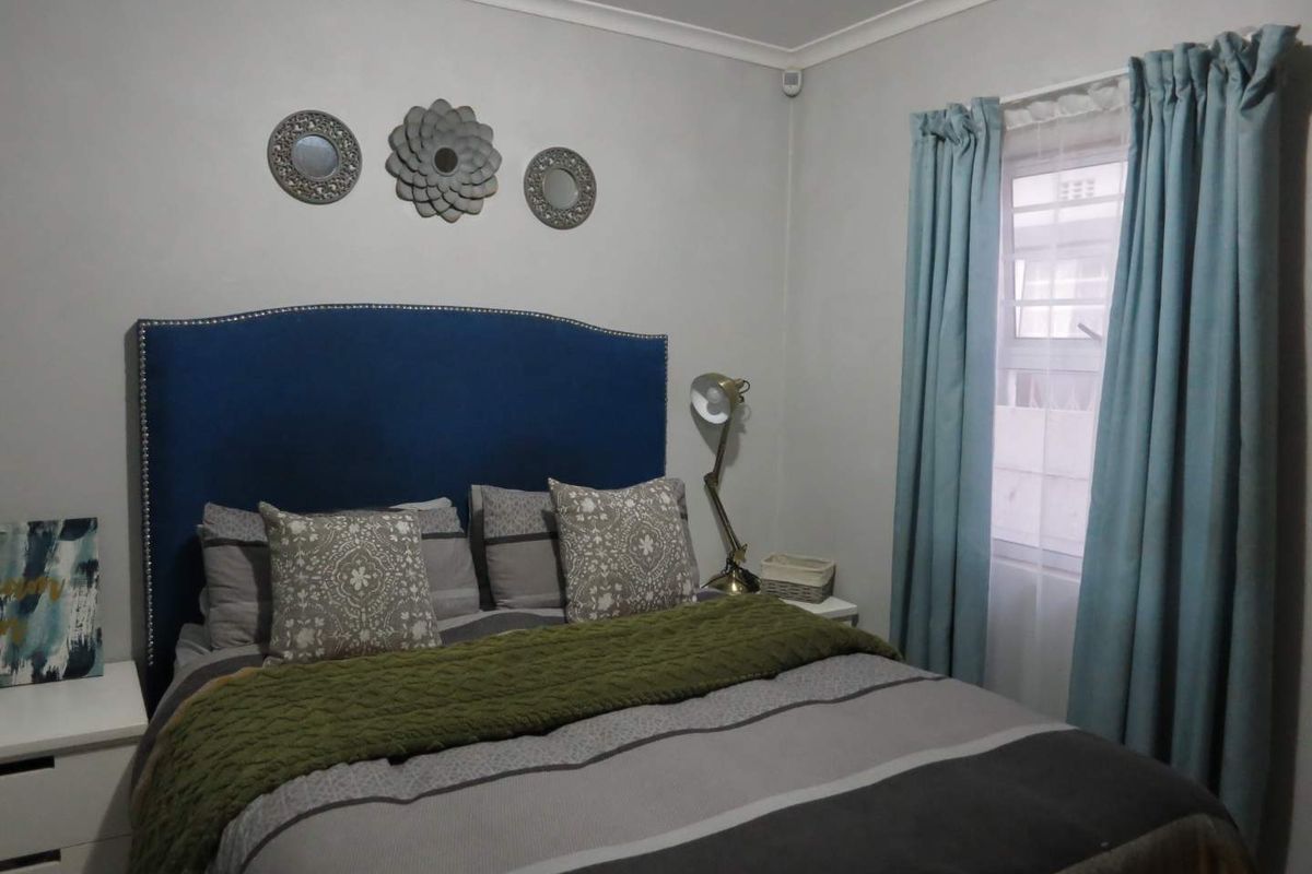 A cozy bedroom featuring neutral wall tones, coving, and a window with curtains, providing a comfortable and functional sleeping space.