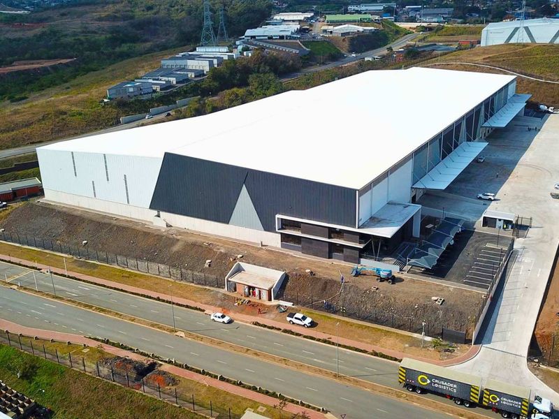 Aerial view of a modern industrial warehouse facility featuring a large-span roof, dedicated loading bays, and secure perimeter fencing with paved access.