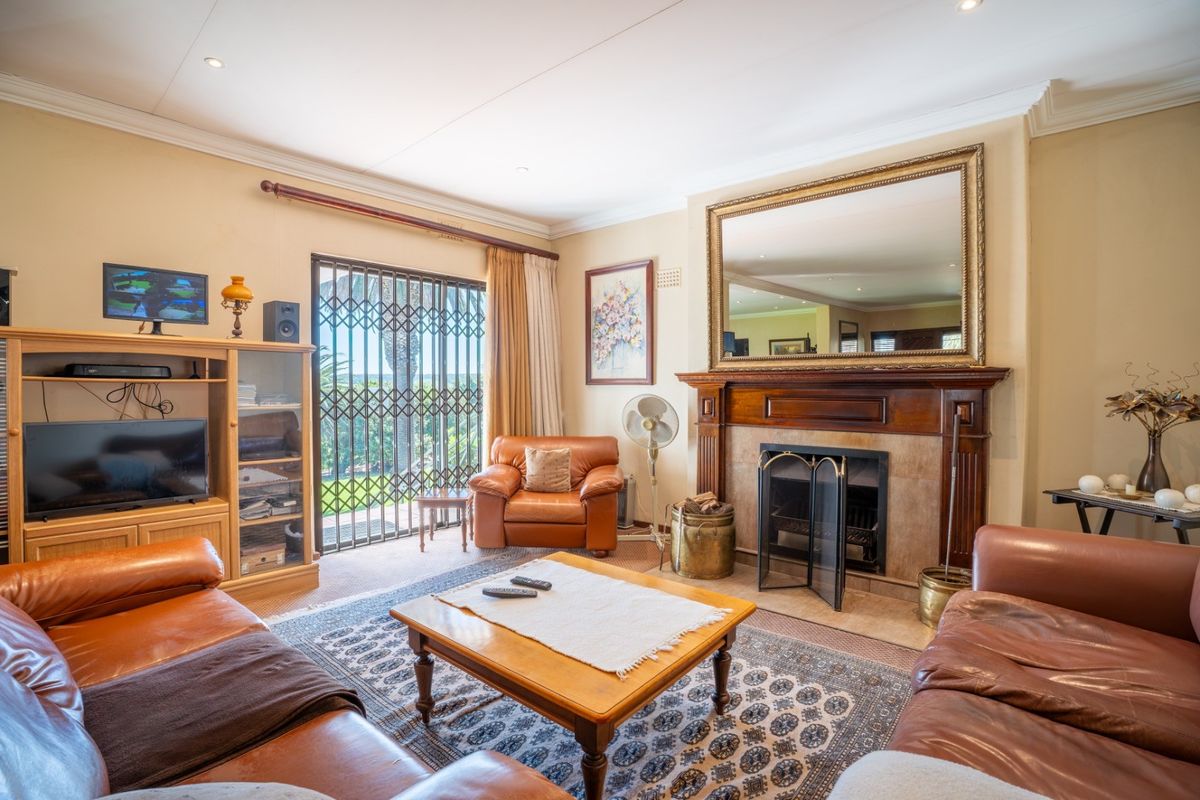 A comfortable living room featuring a classic fireplace with a wooden mantelpiece, recessed lighting, and a sliding glass door leading to the exterior.
