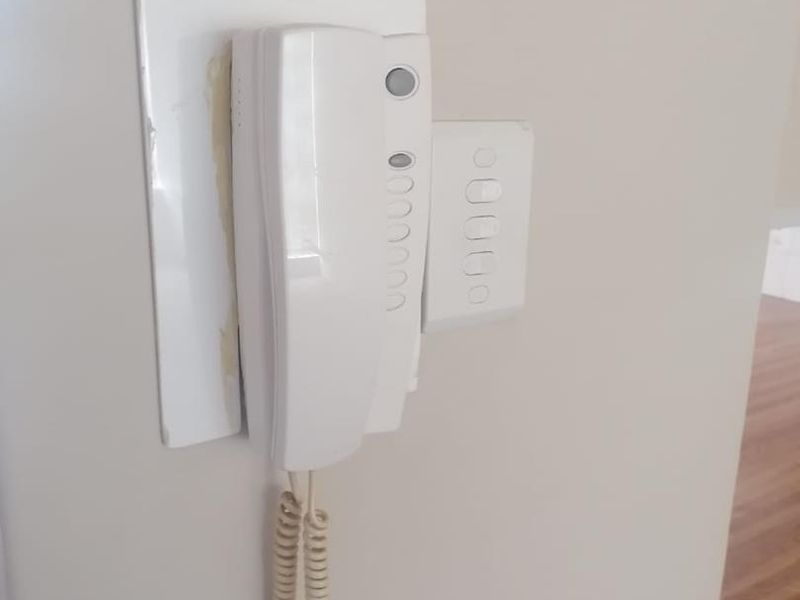 A wall-mounted intercom system and light switch located in the hallway.