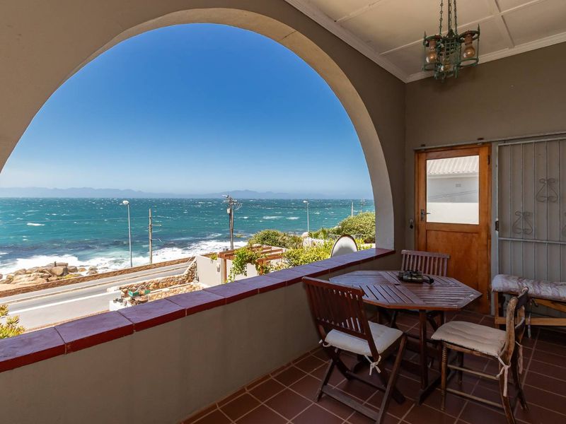 Covered balcony featuring an arched opening with panoramic ocean views, tiled flooring, and direct access to the interior.