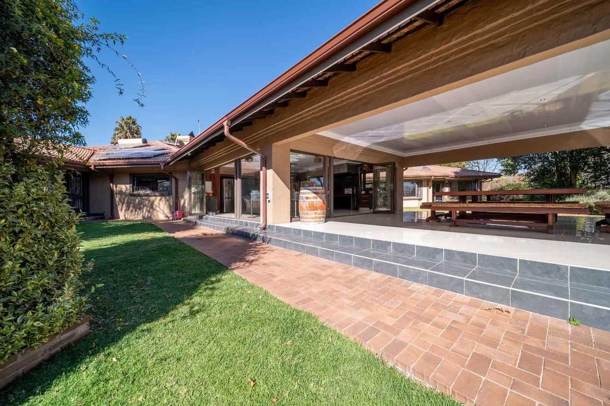 Spacious covered rear patio featuring tiled flooring and recessed lighting, seamlessly connecting to the garden and main living areas through large sliding glass doors.