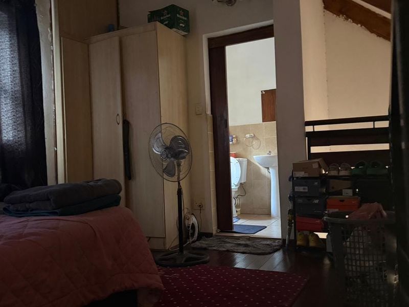 Bedroom featuring exposed timber ceiling beams and a built-in wardrobe, with direct access to an en-suite bathroom.