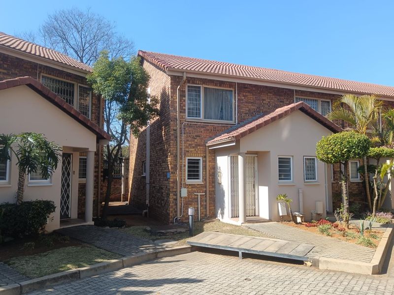 Front view of a face brick apartment complex featuring tiled roofs, paved walkways, and secure entrance points.