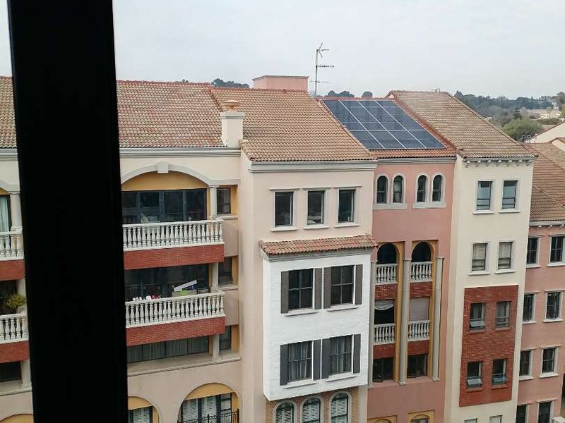 An elevated view of the surrounding apartment complex architecture, featuring tiled roofs, balconies, and installed solar panels.