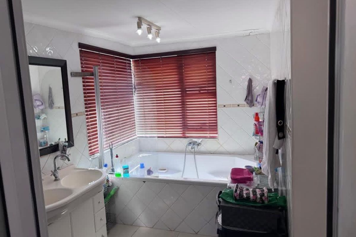 A functional bathroom featuring a built-in corner bathtub, a double vanity with integrated sinks, and tiled wall finishes.