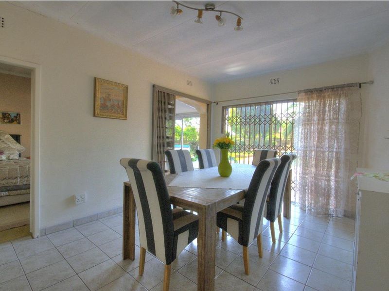 A dining room featuring tiled flooring and a sliding glass door with a security gate, providing access to the outdoor area.