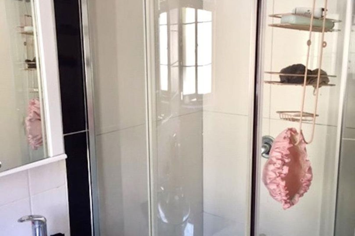 A bathroom featuring a curved glass shower enclosure, mosaic floor tiling, and a modern glass vanity basin with a mirrored cabinet.