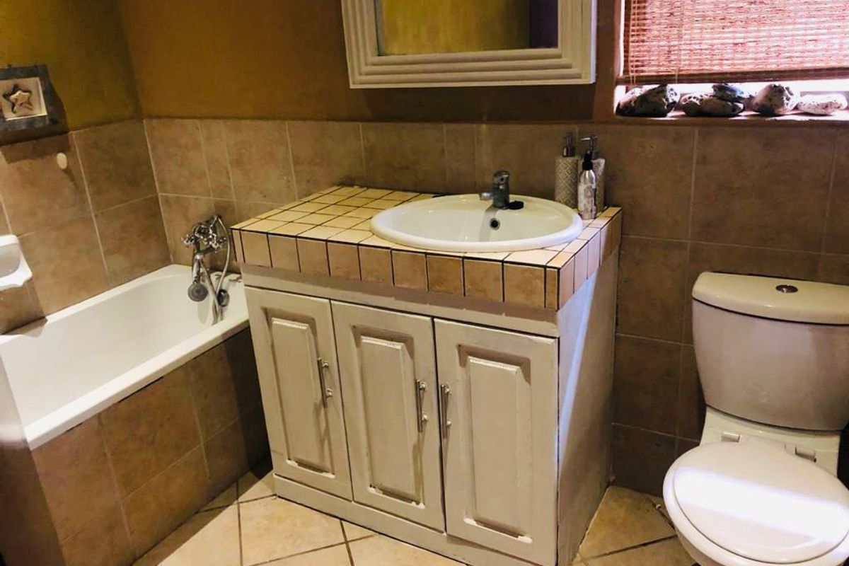 A functional bathroom featuring a tiled vanity with integrated basin, a standard bathtub, and a toilet, finished with neutral wall and floor tiles.