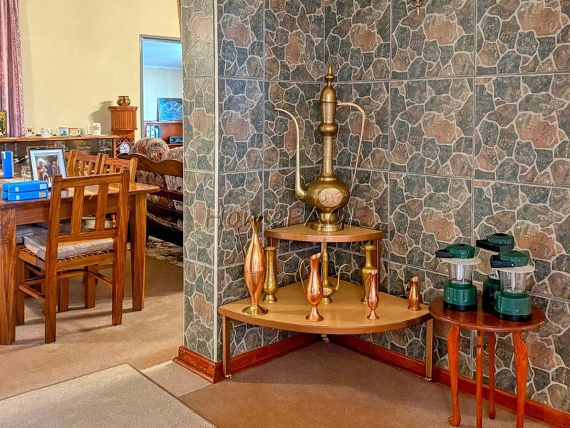 A living area featuring stone-effect wall tiling, a wall-mounted light fixture, and built-in corner shelving, showcasing a dated interior aesthetic.