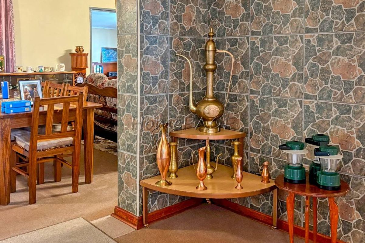 A living area featuring stone-effect wall tiling, a wall-mounted light fixture, and built-in corner shelving, showcasing a dated interior aesthetic.