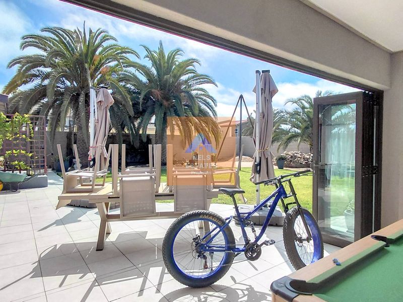 Spacious covered patio area featuring large bi-fold glass doors, providing seamless indoor-outdoor flow to the garden.