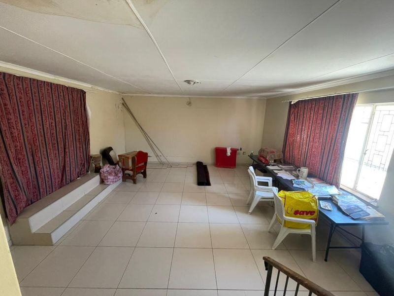 Spacious living area featuring tiled flooring and a raised platform, currently requiring ceiling repairs and cosmetic updates to improve the overall condition.
