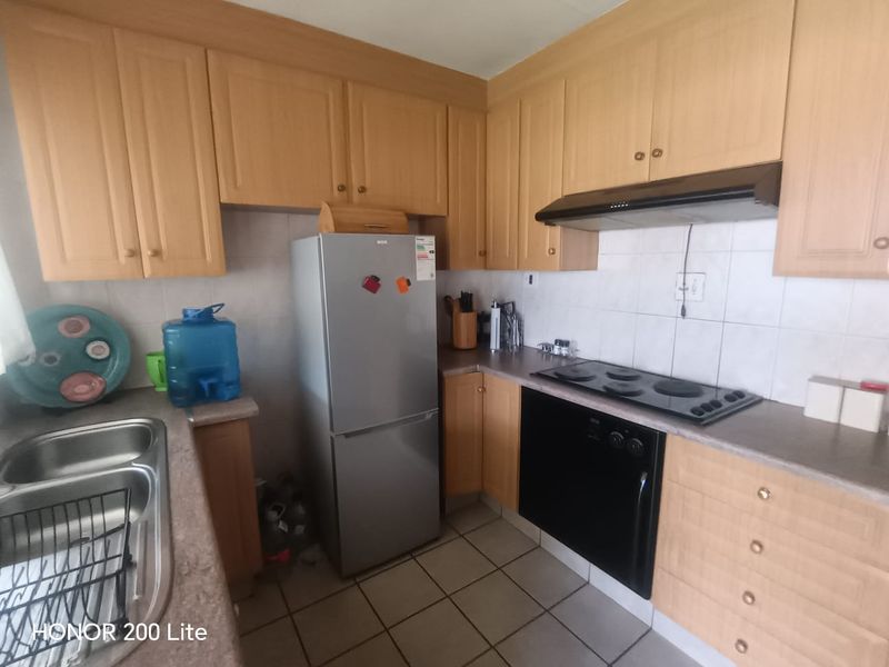 Functional kitchen featuring laminate cabinetry, built-in oven and hob, extractor fan, and tiled splashback with a double bowl stainless steel sink.