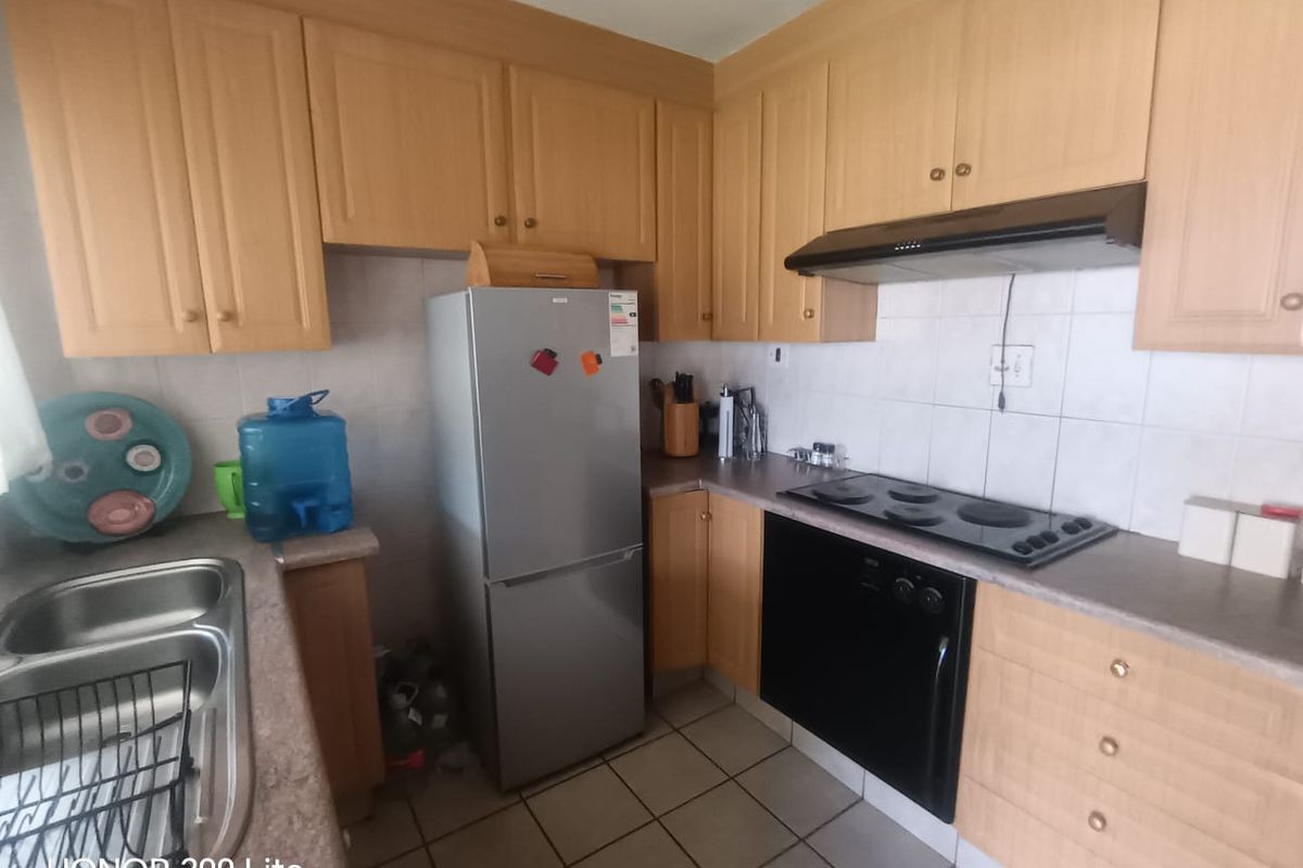 Functional kitchen featuring laminate cabinetry, built-in oven and hob, extractor fan, and tiled splashback with a double bowl stainless steel sink.
