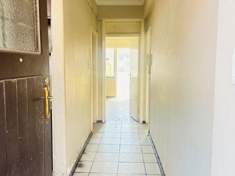 A functional apartment hallway featuring tiled flooring and neutral wall finishes, providing access to the various rooms within the property.