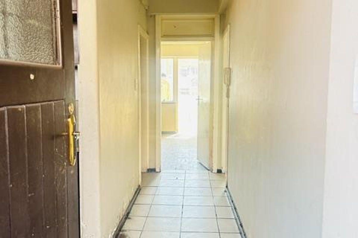 A functional apartment hallway featuring tiled flooring and neutral wall finishes, providing access to the various rooms within the property.