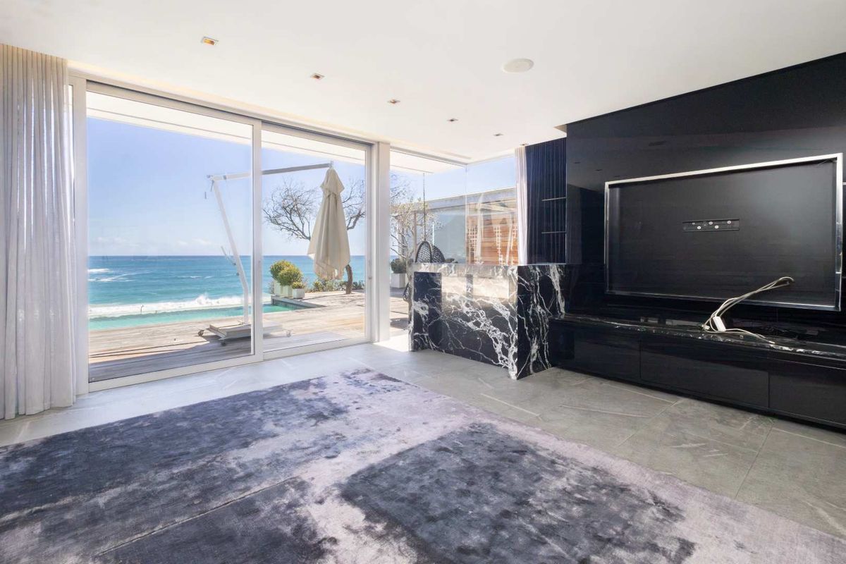 Modern living room featuring large sliding glass doors with ocean views, stone flooring, and a striking marble feature wall with built-in cabinetry.