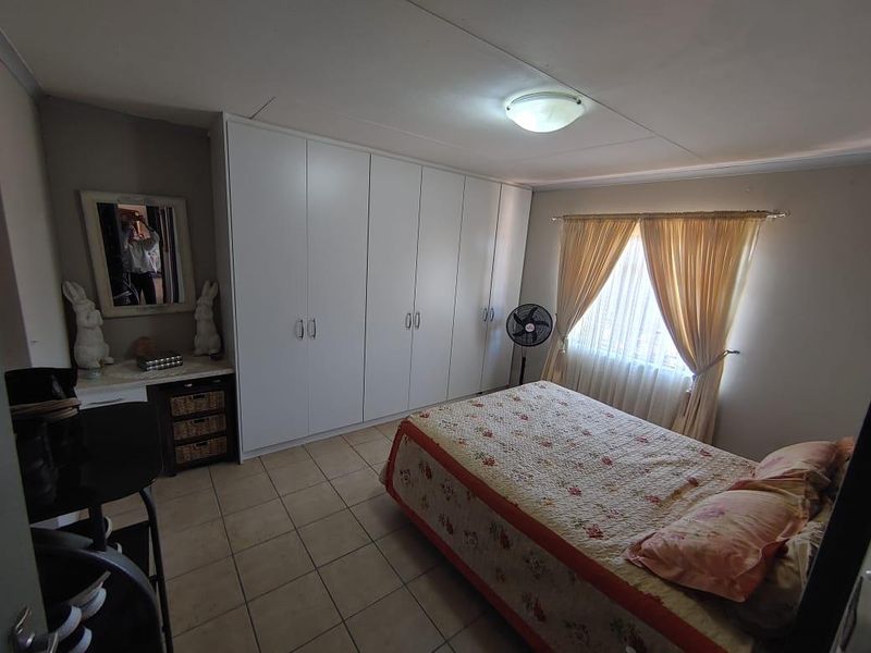 A bedroom featuring tiled flooring and extensive white built-in cupboards providing ample storage space.