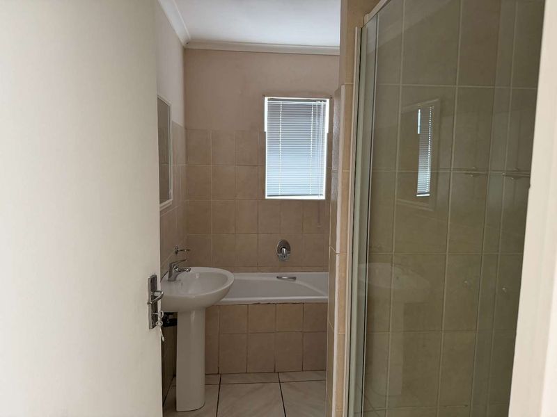 A functional bathroom featuring a pedestal basin, built-in bathtub, and a separate shower enclosure with tiled finishes.
