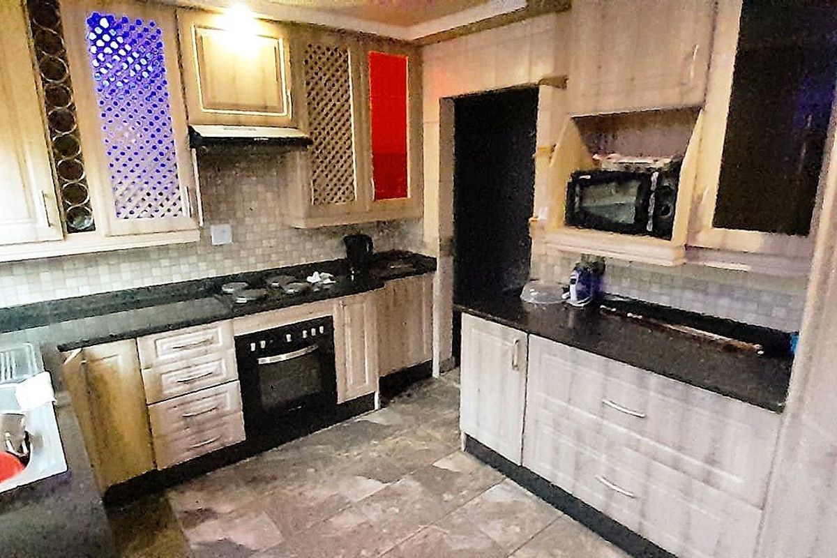 A functional kitchen featuring built-in cabinetry, dark stone countertops, an integrated oven, and a stainless steel double sink.