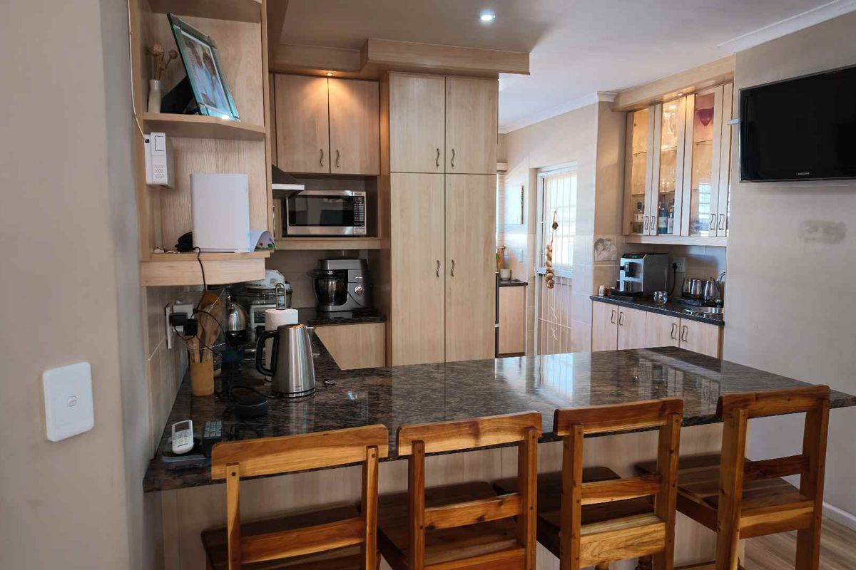 A functional kitchen featuring light wood cabinetry, granite countertops, a breakfast bar, and built-in storage, providing a practical layout for daily use.