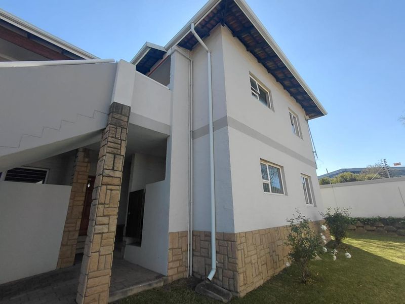 Exterior view of a two-story apartment building featuring stone cladding, white painted walls, and an external staircase.