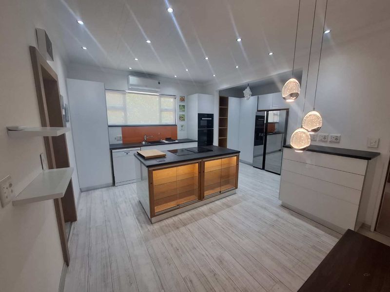 Modern kitchen featuring a central island, built-in oven, sleek cabinetry, and contemporary pendant lighting, offering a clean and functional culinary space.