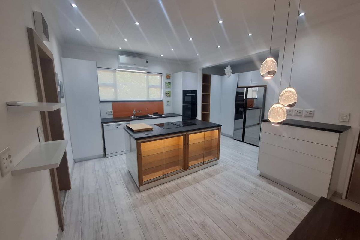 Modern kitchen featuring a central island, built-in oven, sleek cabinetry, and contemporary pendant lighting, offering a clean and functional culinary space.