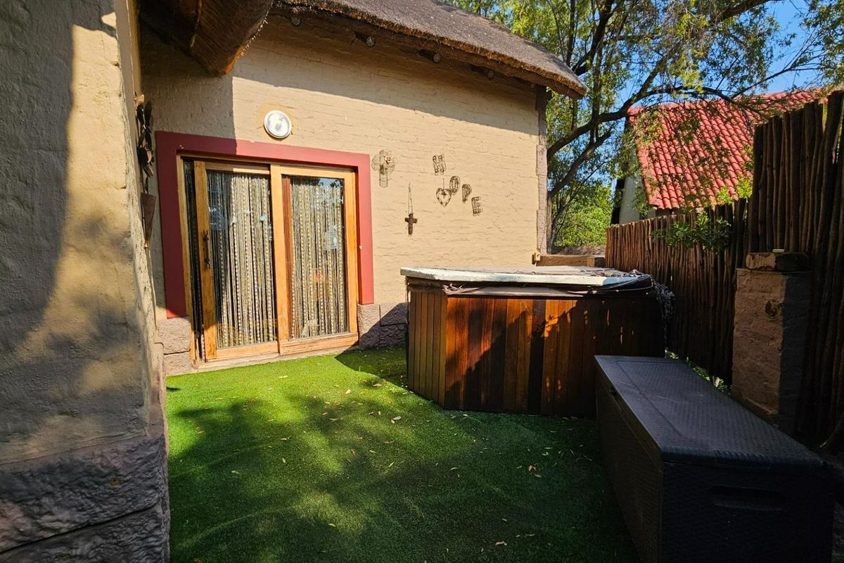 A private rear garden area featuring a wooden hot tub, artificial lawn, and sliding glass door access to the main dwelling.