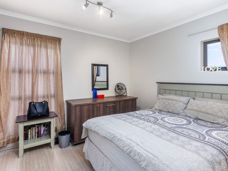 A well-maintained bedroom featuring laminate flooring, a built-in wardrobe, and a modern ceiling spotlight track, offering a clean and functional living space.