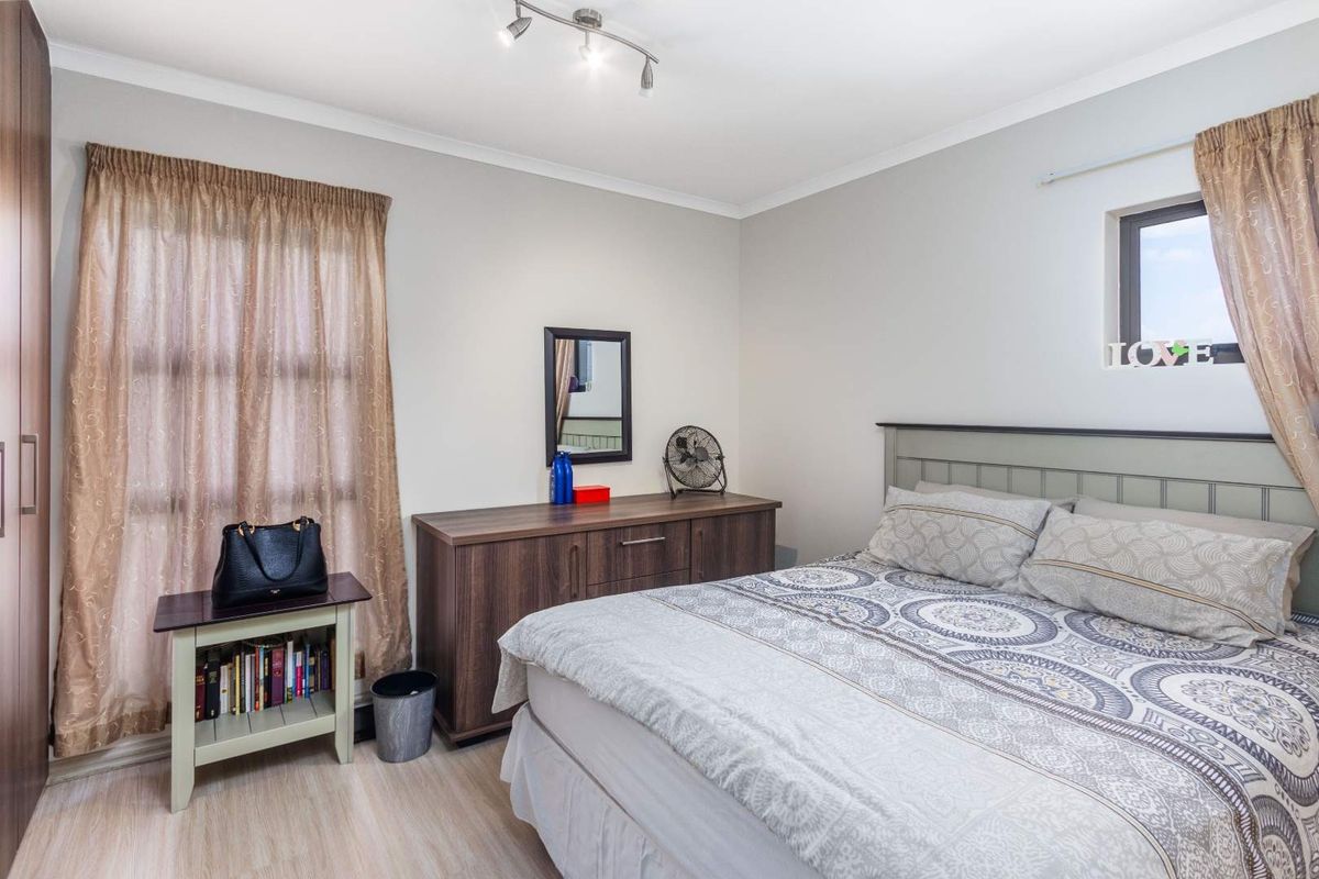A well-maintained bedroom featuring laminate flooring, a built-in wardrobe, and a modern ceiling spotlight track, offering a clean and functional living space.