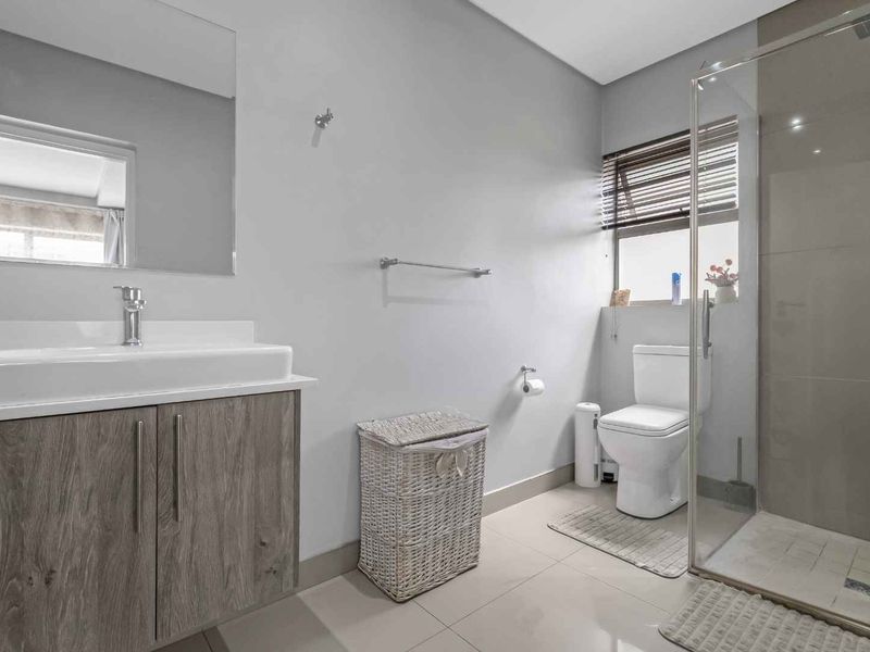 A modern, well-maintained bathroom featuring a vanity with basin, a glass-enclosed shower, and neutral tiled finishes.