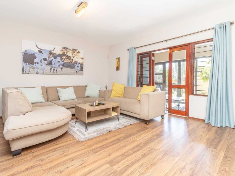 A bright living room featuring laminate flooring and timber-framed glass sliding doors that provide access to the outdoor area.