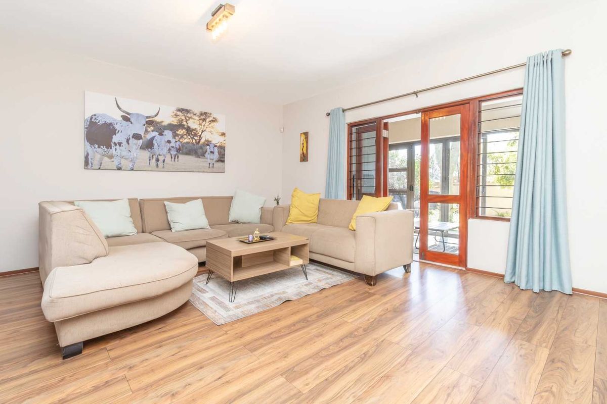 A bright living room featuring laminate flooring and timber-framed glass sliding doors that provide access to the outdoor area.