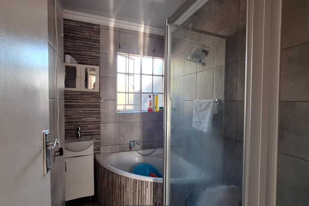 A functional bathroom featuring a corner bathtub, separate shower enclosure, and a vanity basin with tiled wall finishes.