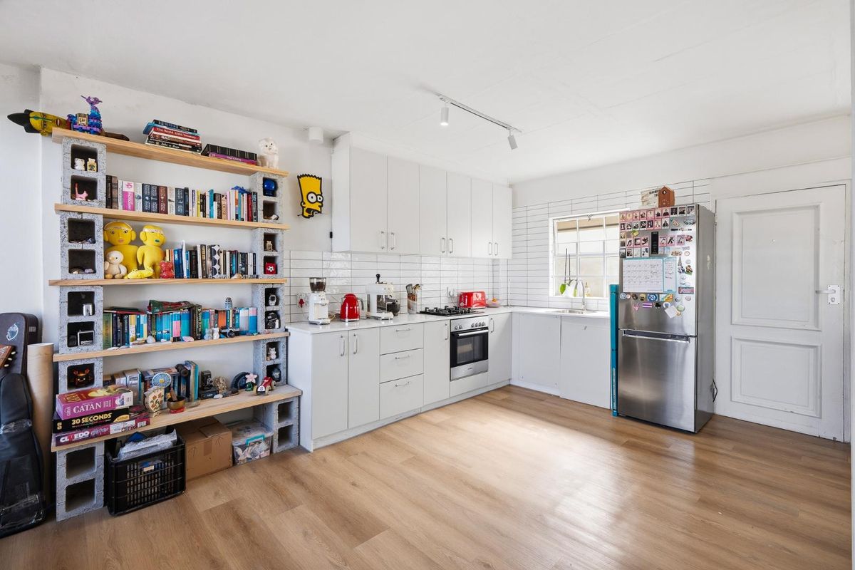 A bright kitchen featuring white cabinetry, subway tile backsplash, built-in oven, gas hob, and modern laminate flooring.