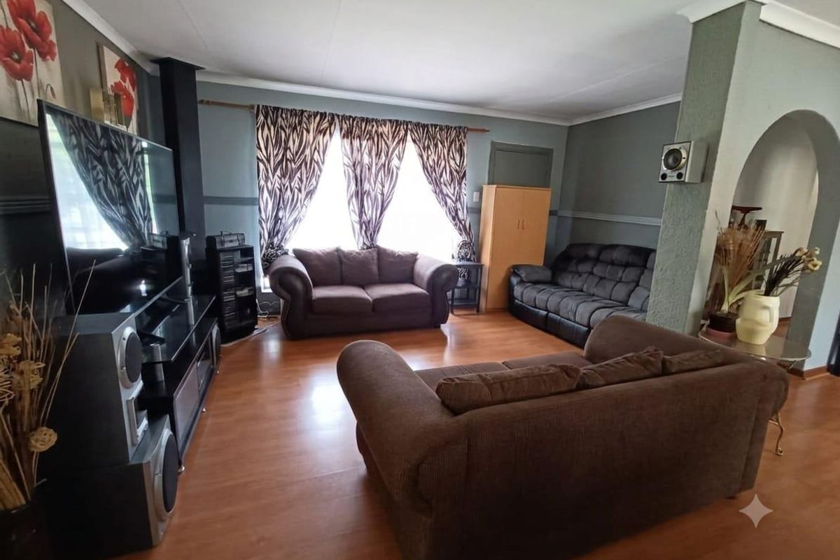 Spacious living room featuring laminate wood flooring, an arched entryway, and a built-in fireplace, offering a comfortable and functional layout.
