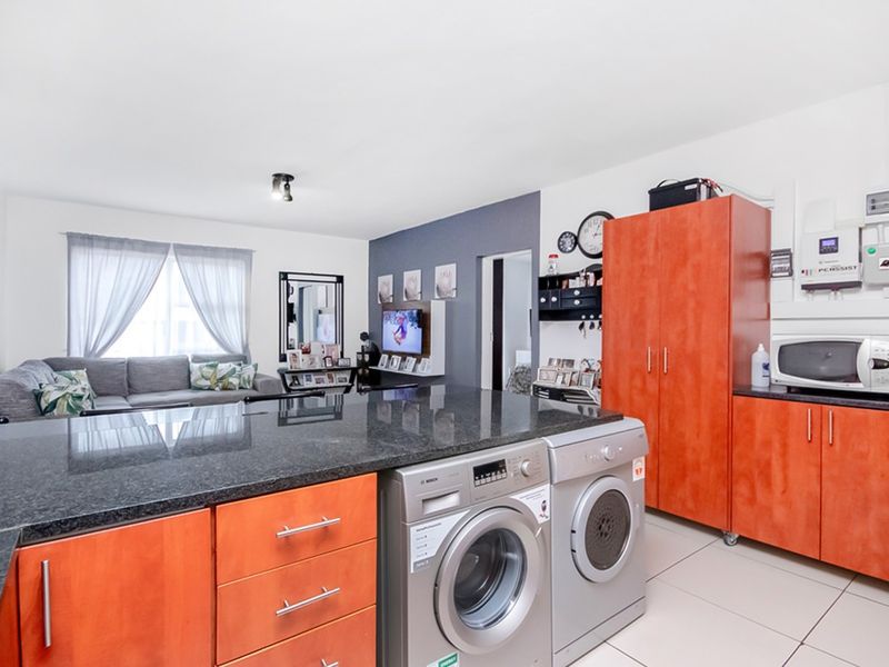 Open plan living area featuring a kitchen island with granite countertops, integrated laundry appliances, and a wall-mounted inverter system.