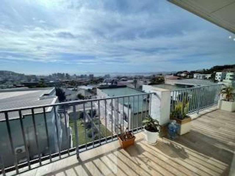 Spacious balcony featuring a metal balustrade and tiled flooring, offering expansive elevated views of the surrounding urban landscape.