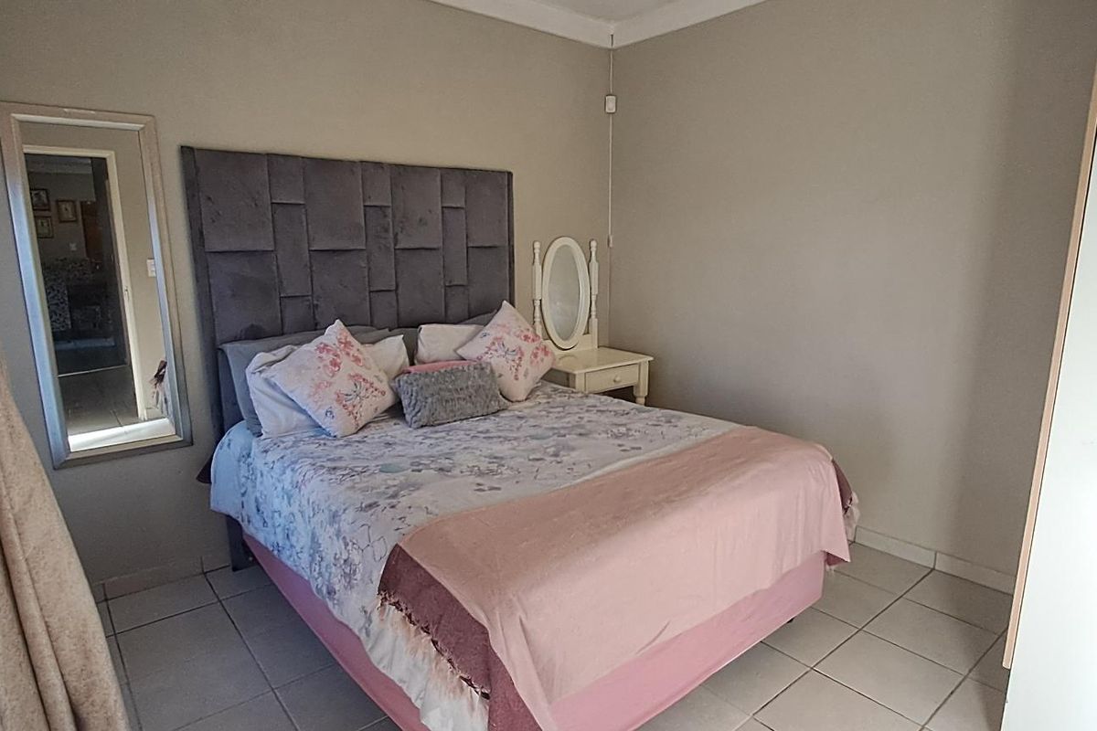 A functional bedroom featuring tiled flooring, neutral wall finishes, and a built-in cupboard, offering a clean and simple living space.