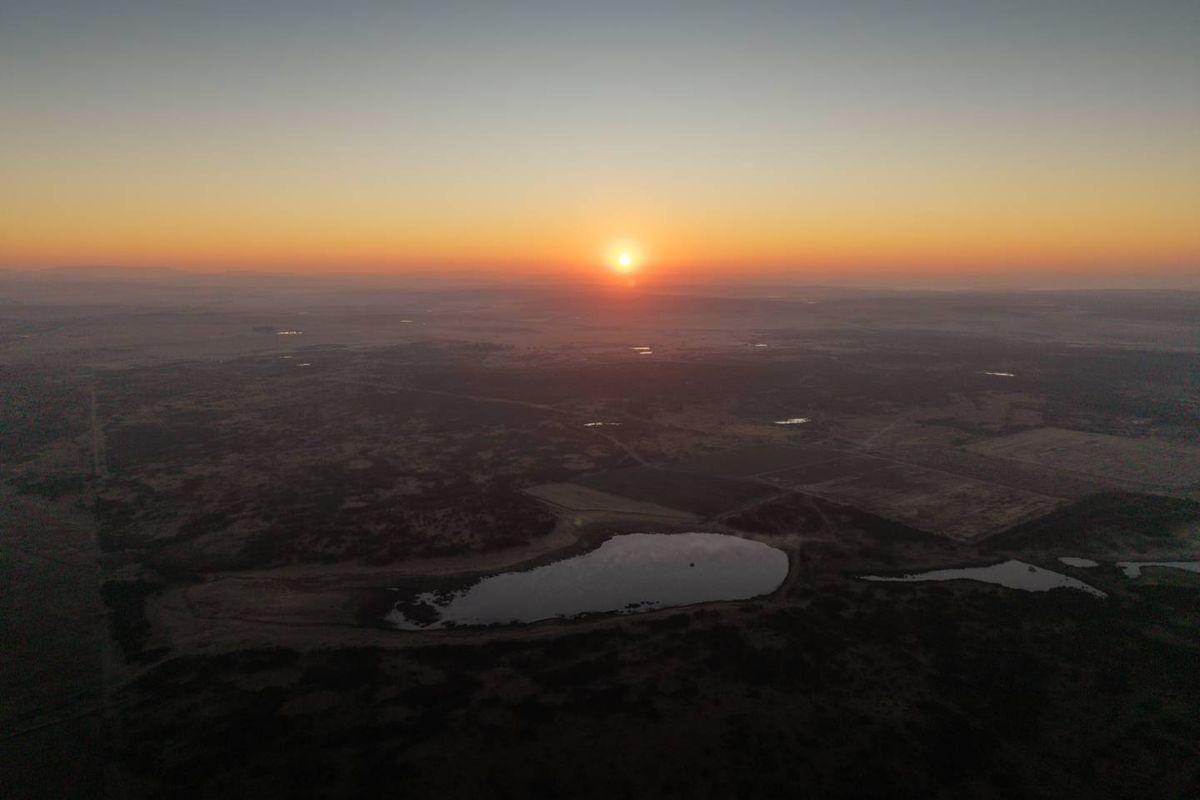 An aerial view of the surrounding landscape at sunrise, showcasing the natural terrain and water features of the property's location.