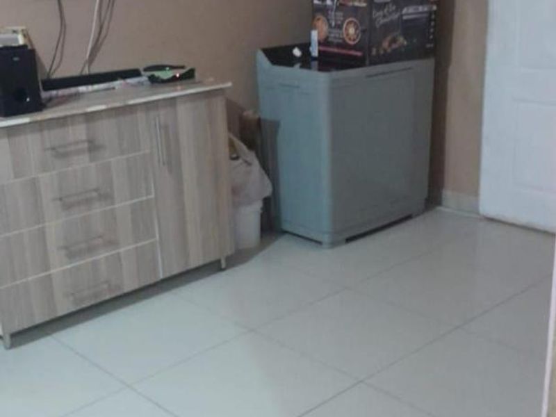 A living area featuring tiled flooring and neutral wall paint, currently utilized for storage and media equipment.