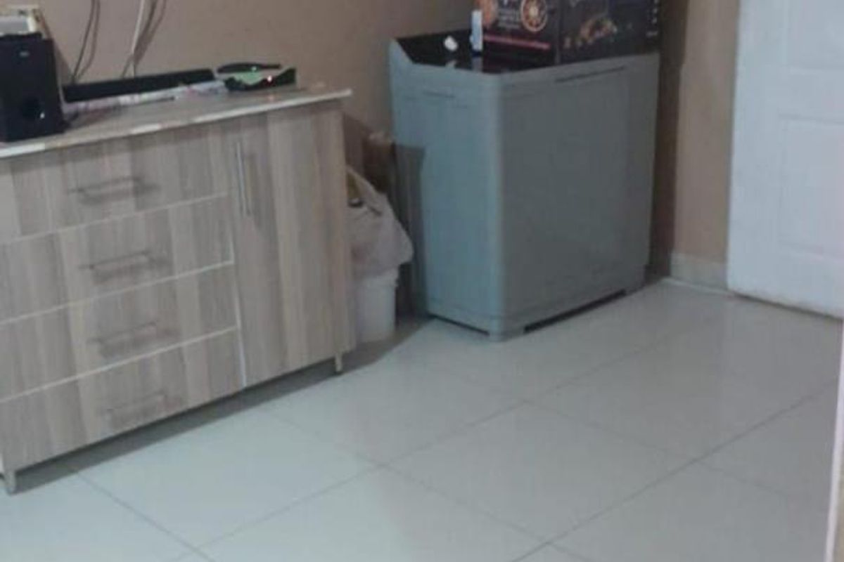 A living area featuring tiled flooring and neutral wall paint, currently utilized for storage and media equipment.