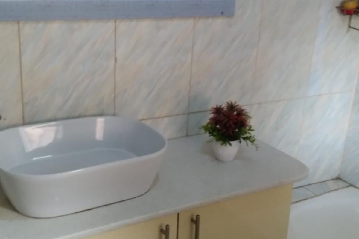 A bathroom vanity area featuring a modern vessel sink, built-in cabinetry, and wall-mounted mirror with decorative tile accents.